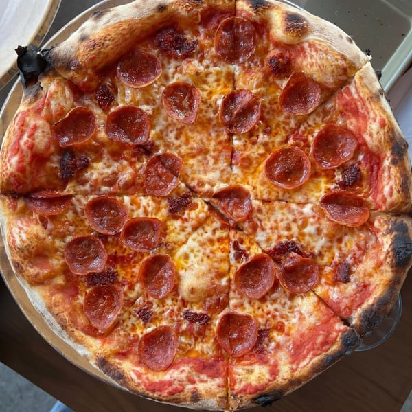 Close-up overhead view of a whole pepperoni pizza with a charred crust, sliced into eight pieces.